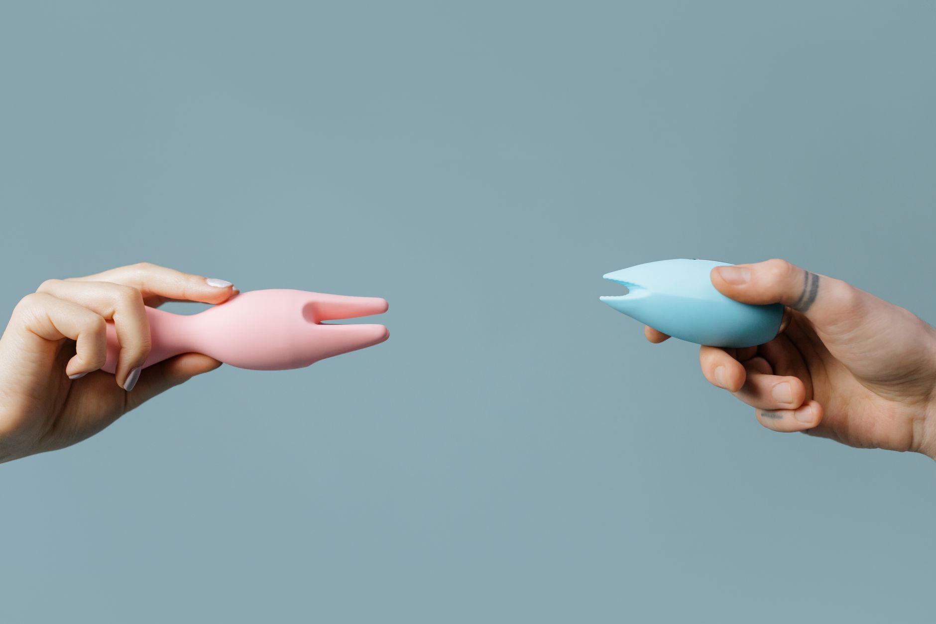 Hands holding colorful silicone vibrators together, symbolizing intimacy and connection
