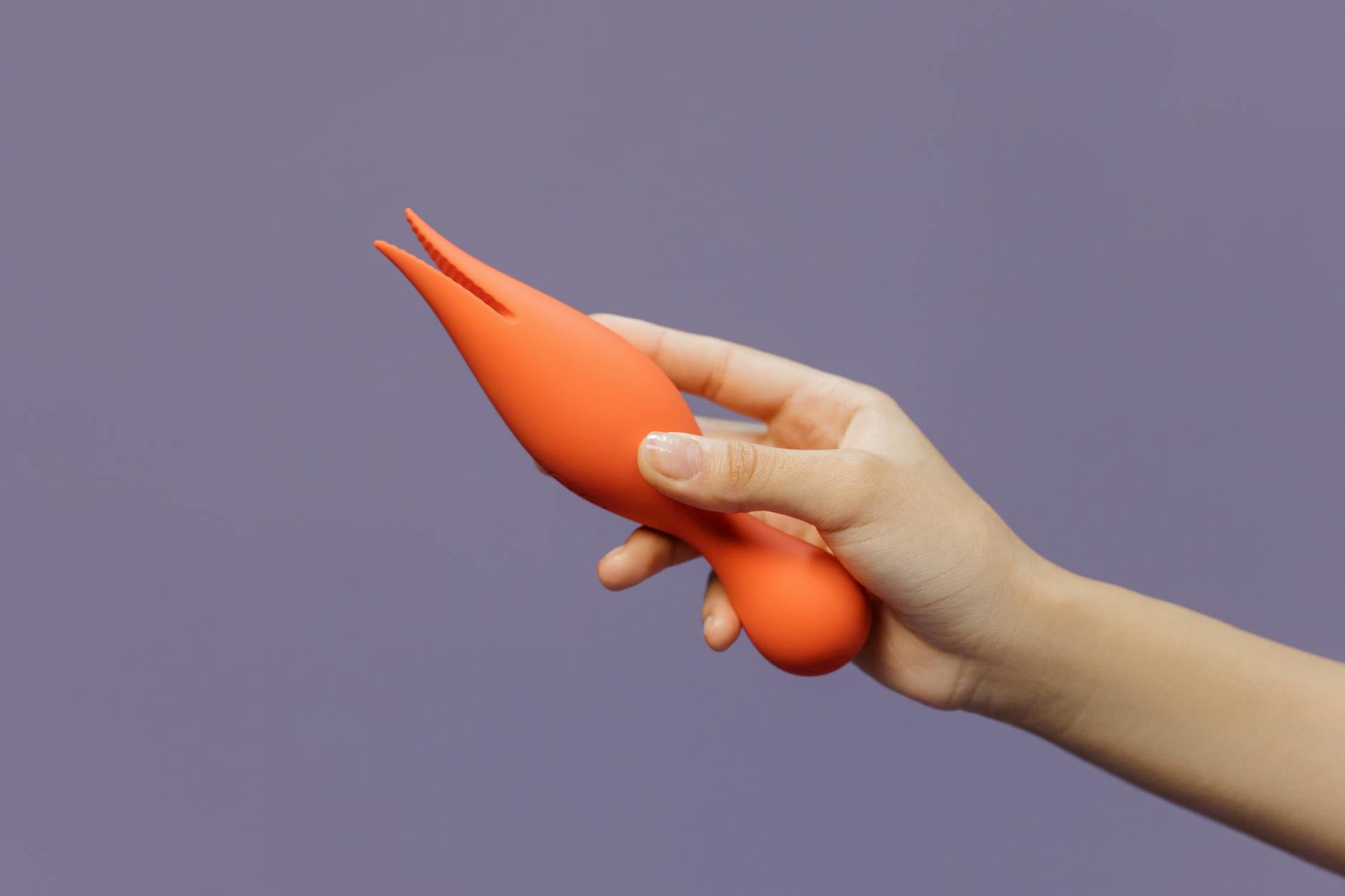 Close-up of a hand holding a lemon vibrator against a purple backdrop, showcasing modern sensuality and intentional pleasure.