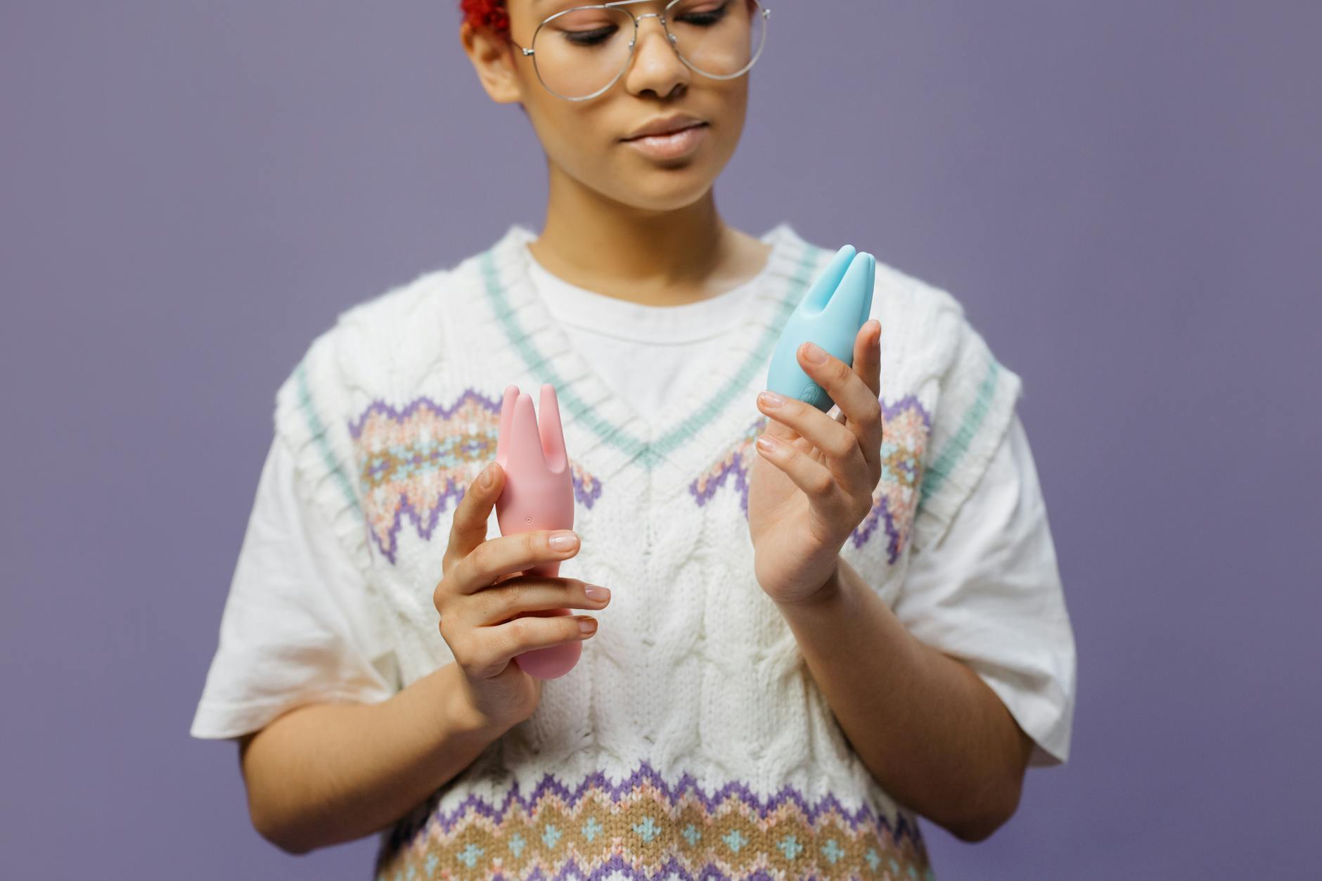 Woman holding silicone clitoral vibrators in contemplative moment