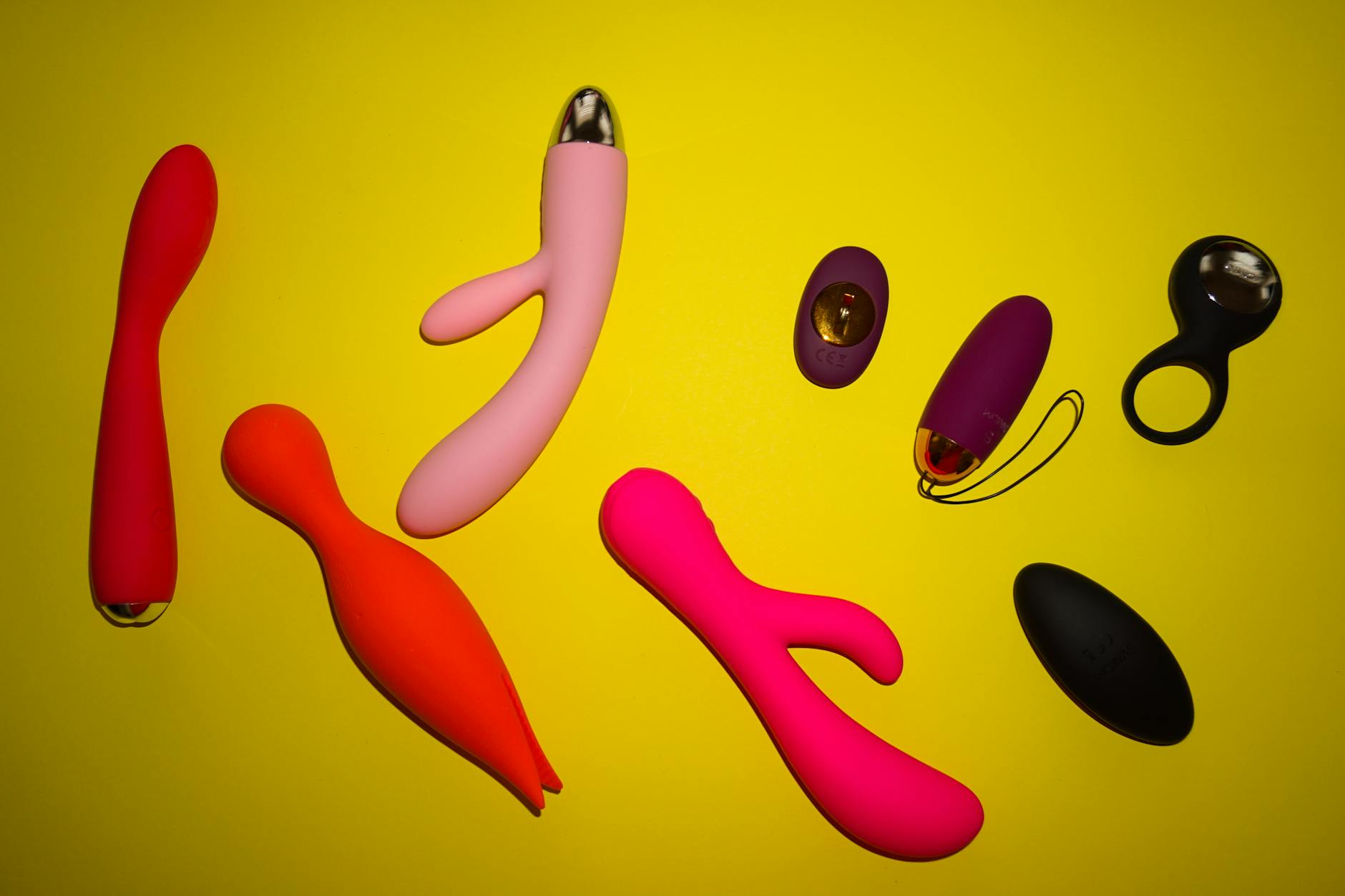 A vibrant collection of clitoral vibrators and adult toys arranged on a bright yellow surface