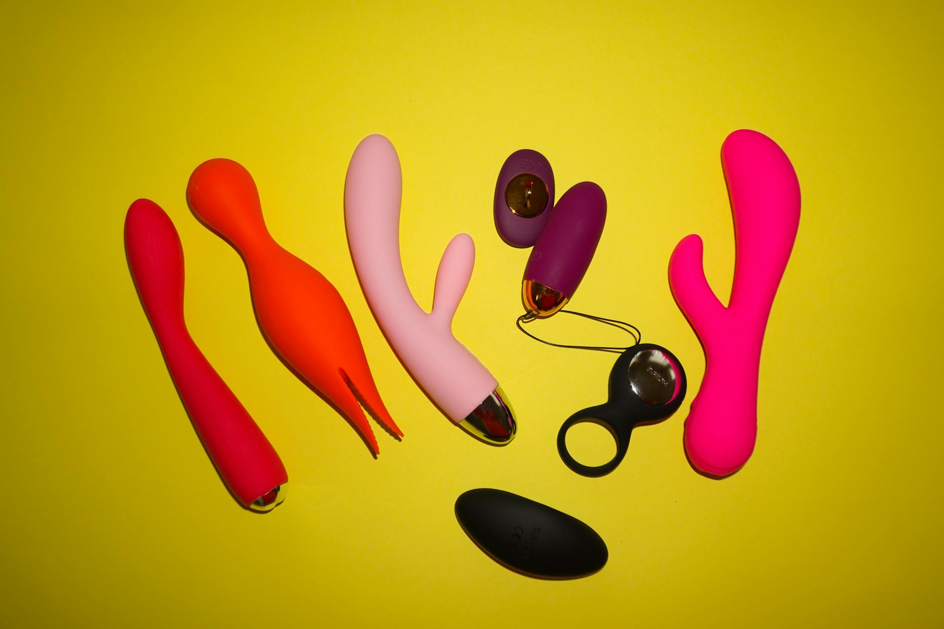 Hands holding soft silicone vibrators in pastel colors against a neutral background